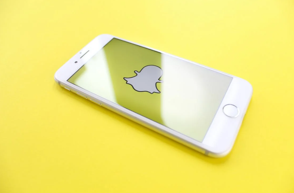 a side view of a smartphone with a Snapchat icon on it on a yellow table