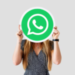 A girl holding an icon of the WhatsApp application